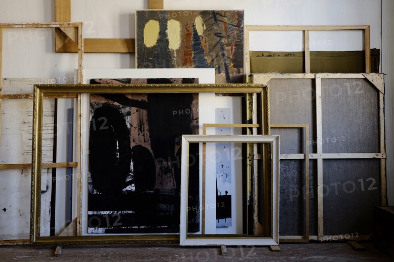 Paintings and frames leaning on wall