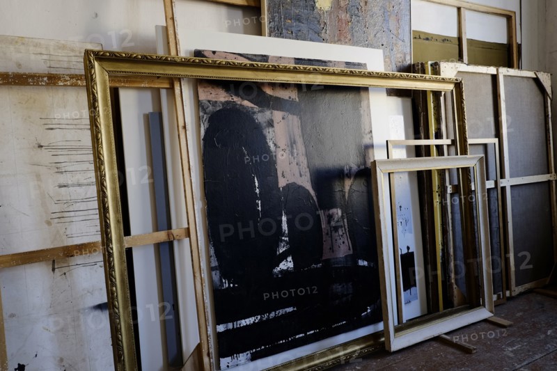 Paintings and frames leaning on wall