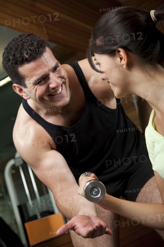 Middle Eastern man helping woman lift weights