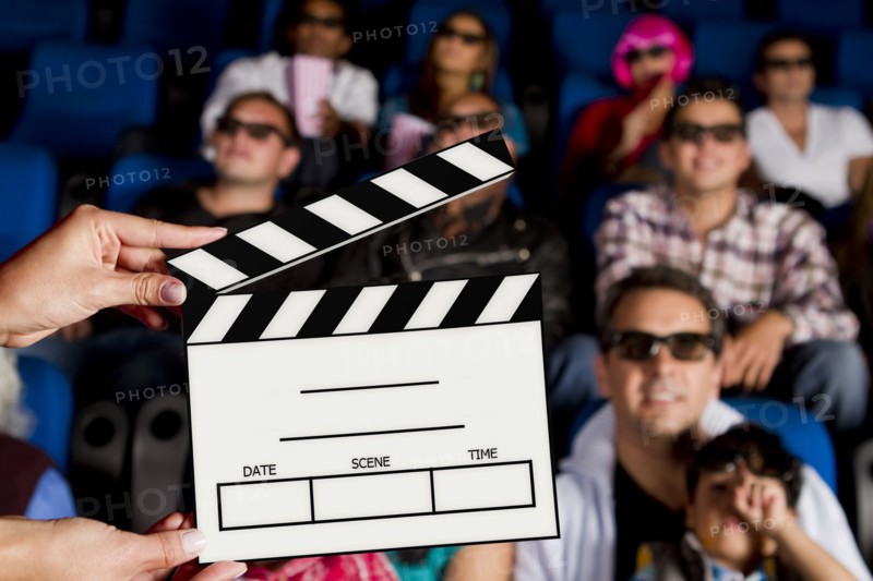 Clapperboard in front of Hispanic people in movie theater