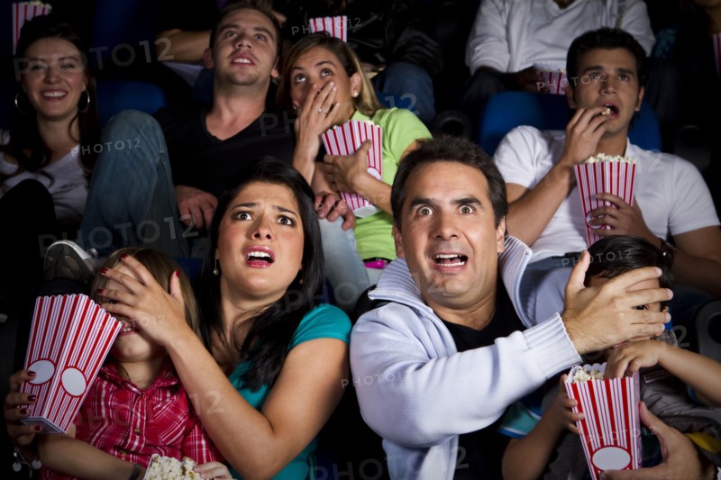 Frightened Hispanic family watching film in movie theater