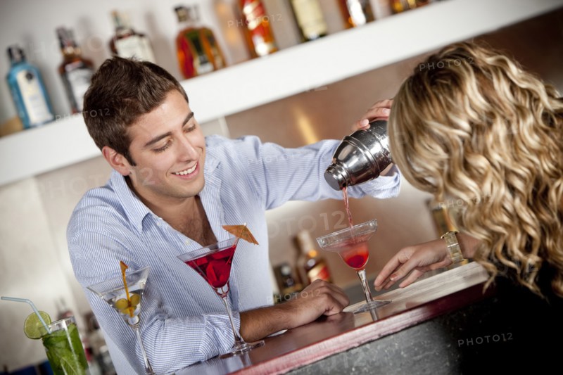 Hispanic bartender pouring cocktail for customer