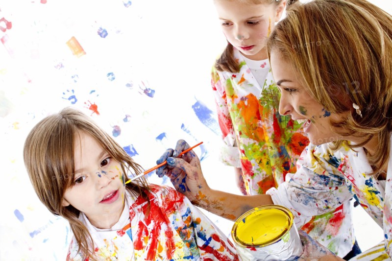 Messy Hispanic mother painting daughter's face