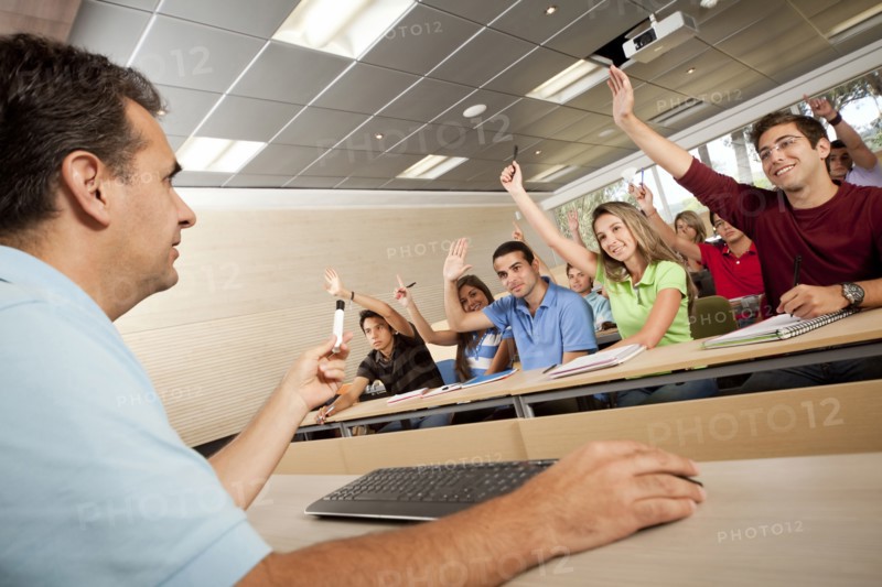 Hispanic college students raising arms in classroom