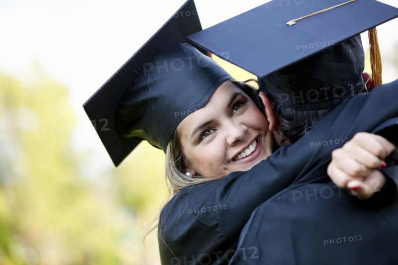 Graduating Hispanic couple in cap and gown hugging