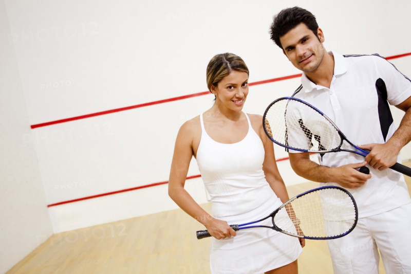 Hispanic couple holding squash racquets
