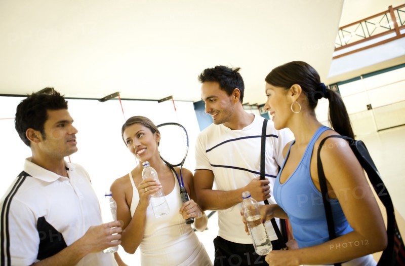 Hispanic couples on squash court drinking water