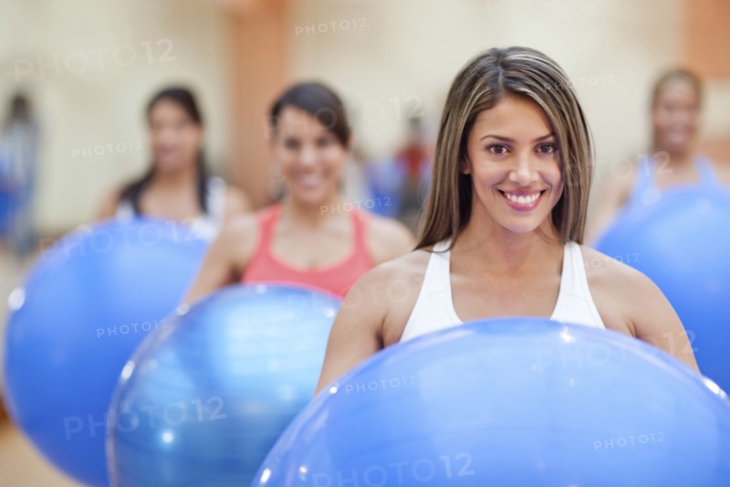 Hispanic women using exercise balls in gym