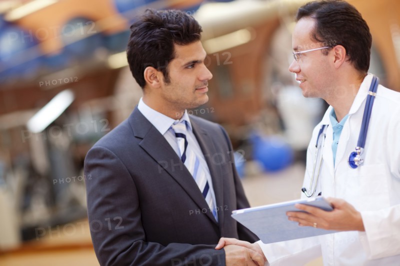 Hispanic doctor and businessman shaking hands