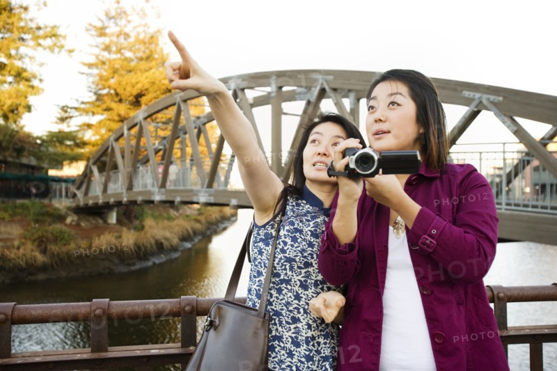 Chinese mother and daughter taking photographs outdoors