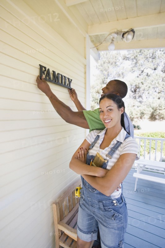 Couple hanging family sign on house