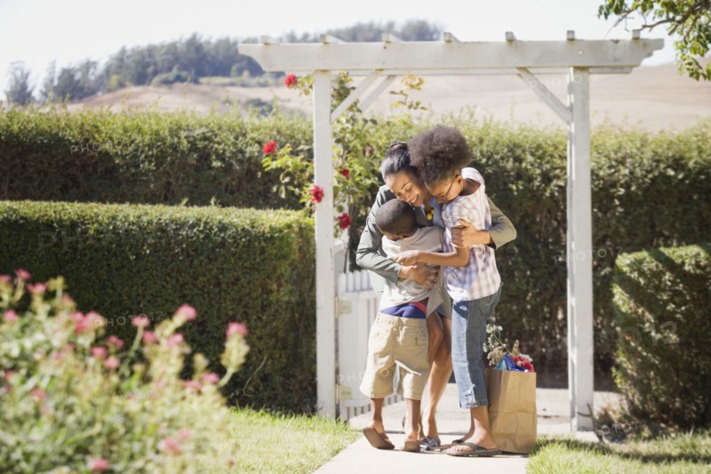 Mother with groceries hugging children