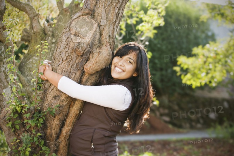 Hispanic woman hugging tree