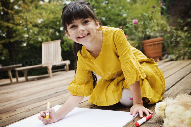 Mixed race girl coloring on deck