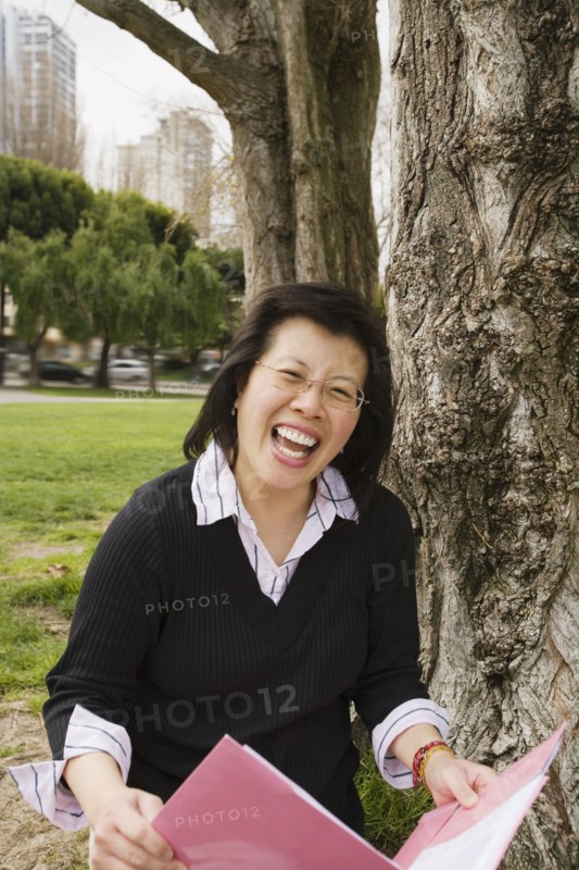 Chinese woman holding folder next to tree