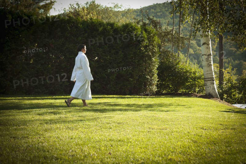 Woman walking across lawn in bathrobe