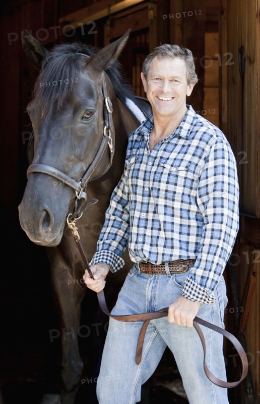 Caucasian man holding horse's bridle