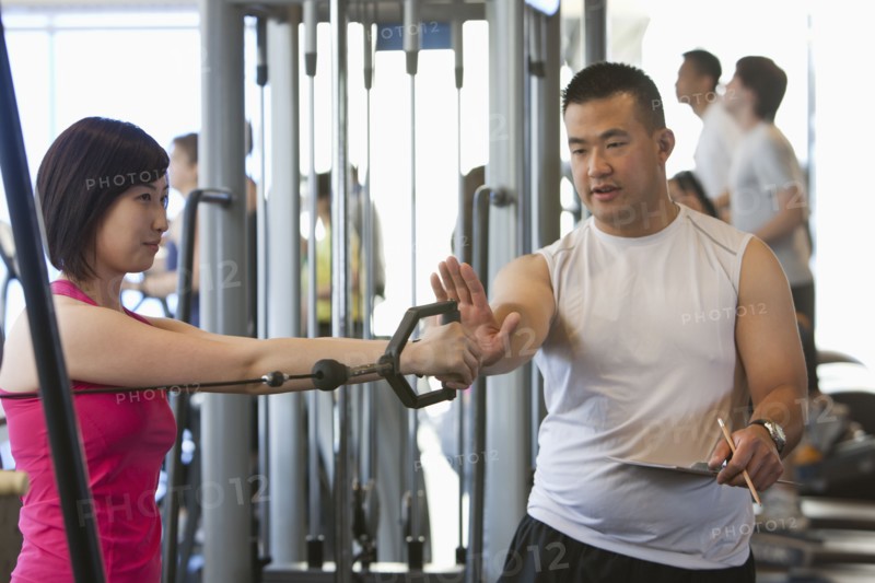 Woman working with personal trainer in health club