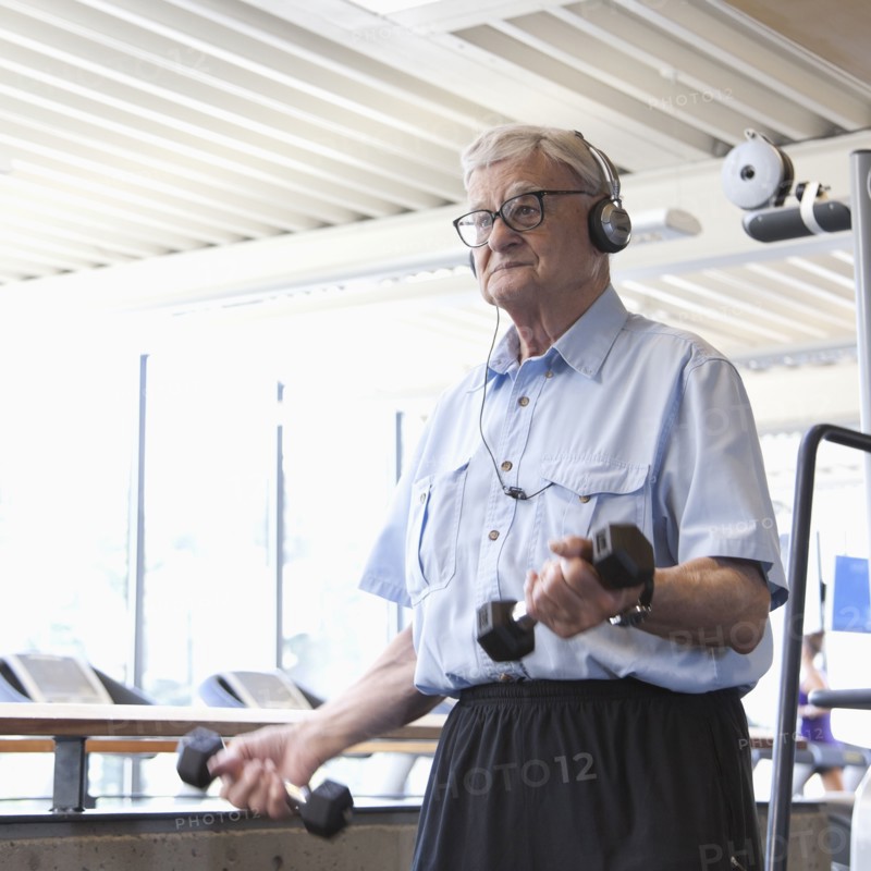 Senior man lifting weights in health club