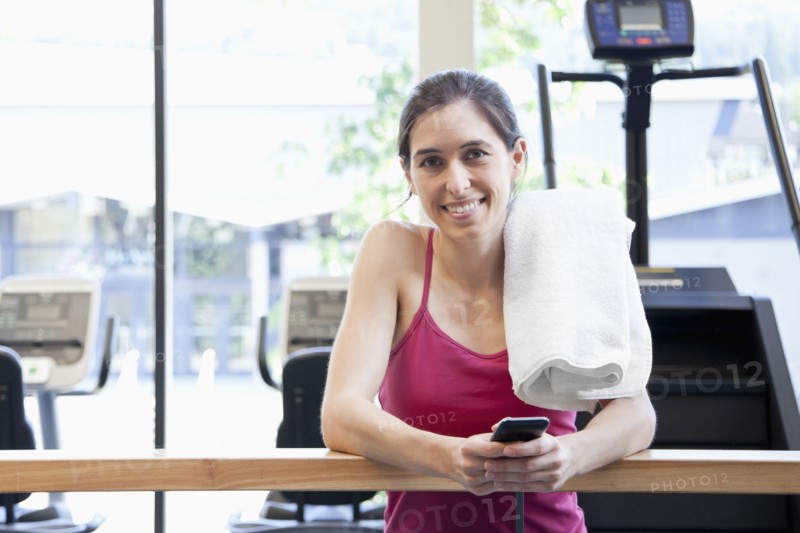 Woman holding cell phone in health club