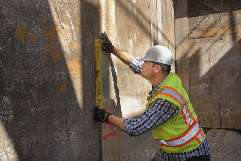 Caucasian construction worker holding level against wall