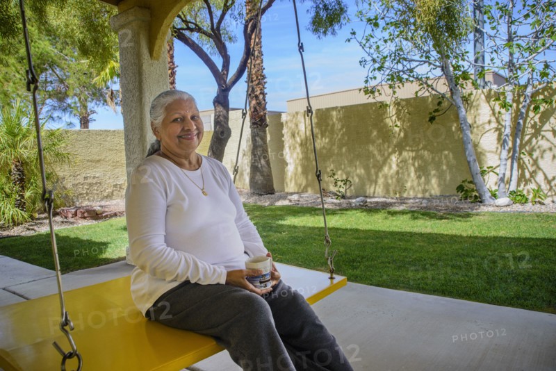 Older indian woman drinking coffee on patio swing