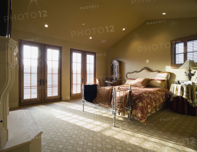 Master bedroom with vaulted ceiling and window light spilling through double french doors