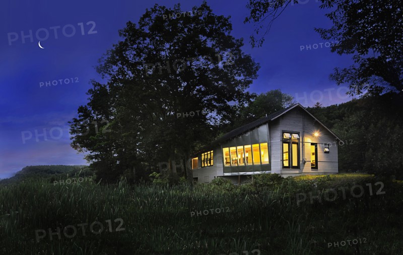 Illuminated cabin with clapboard siding on landscape at night