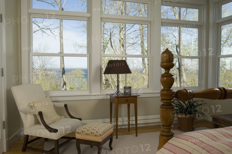 Detail bedroom with several windows and armchair
