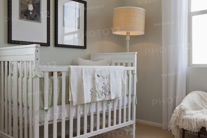 Baby's crib with floor lamp and picture frames in the house