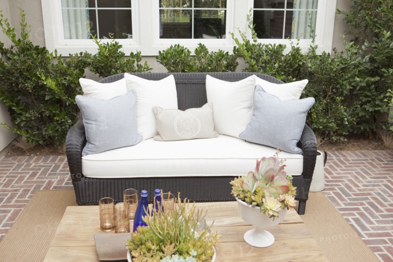 Wicker couch with cushions on brick flooring at a patio