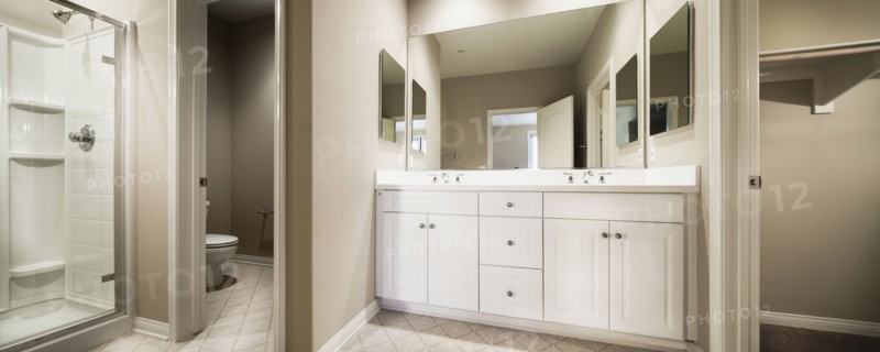 Bathroom with cropped commode and washbasin with cabinets at mirror