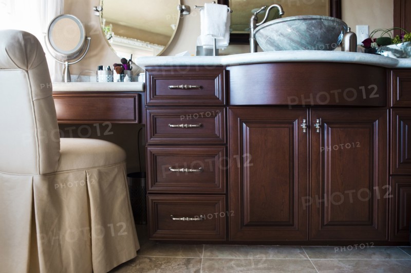 Chair with brown cabinets and mirrors in bathroom at home