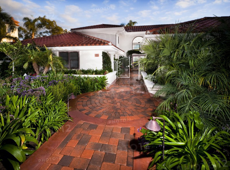Brick walkway along plants leading to open gate at Laguna Niguel