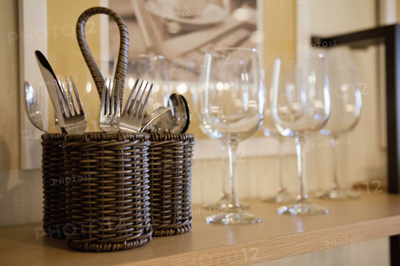 Close-up of cutlery and wine glasses on shelf in cabinet