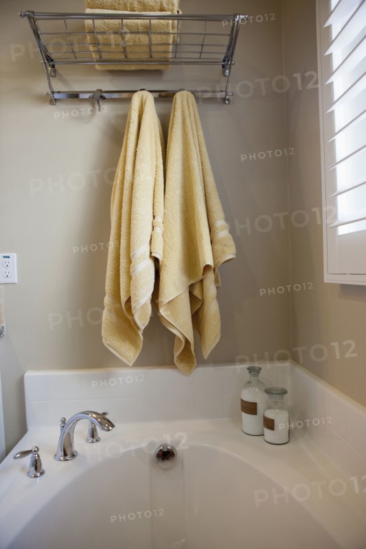 Bathroom with hanging towels over cropped bathtub