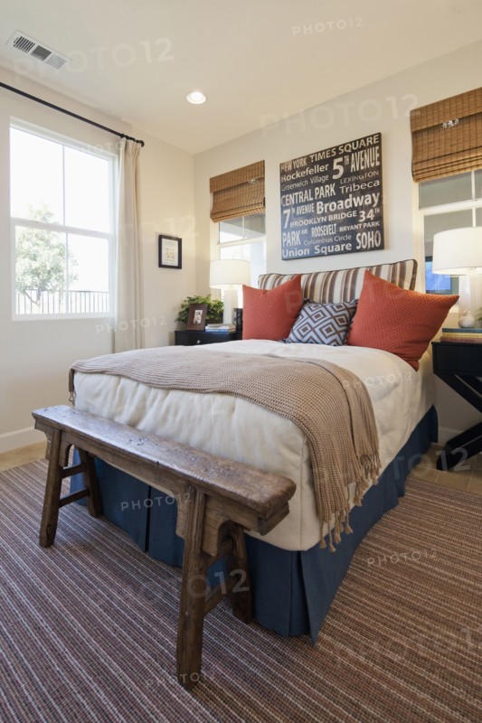 Arranged pillows on tidy bed on carpet floor in the bedroom at home