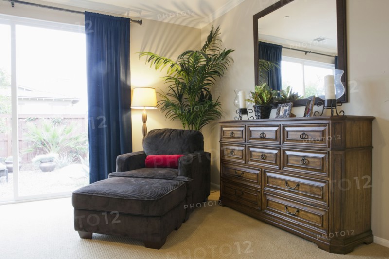 Armchair and ottoman by sideboard in bedroom