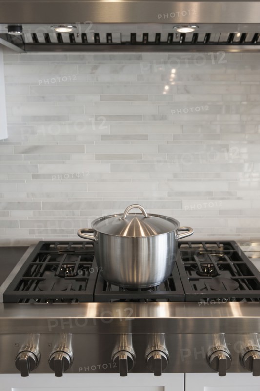Sauce pan on stove against backsplash in kitchen