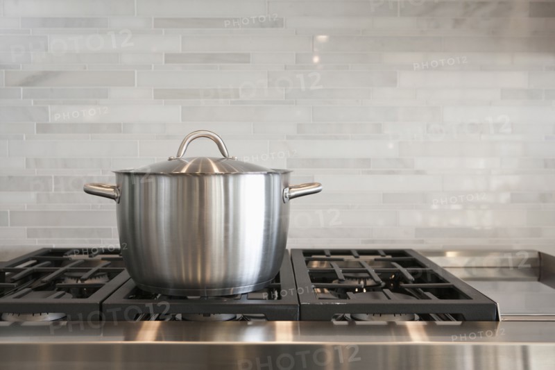 Sauce pan on burner with backsplash in kitchen