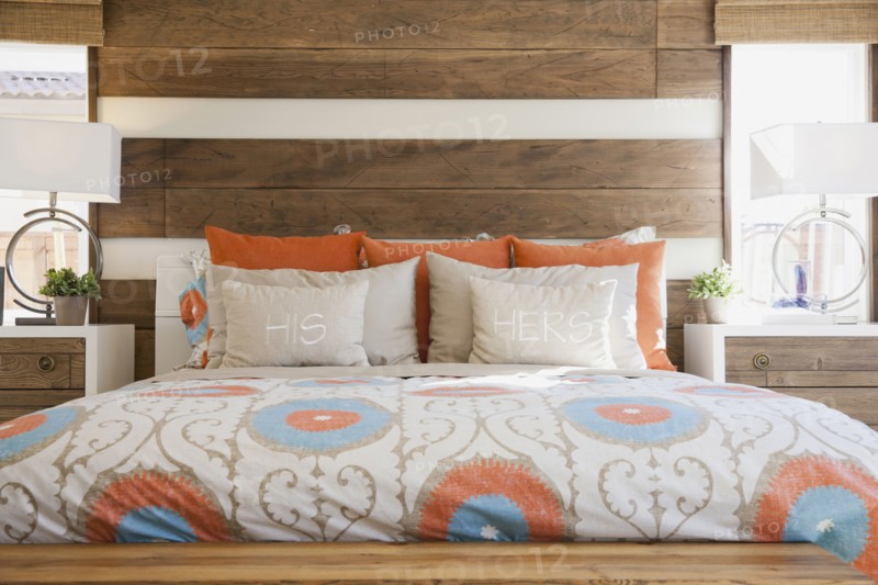 Cozy and tidy bed with wood paneled wall in contemporary bedroom