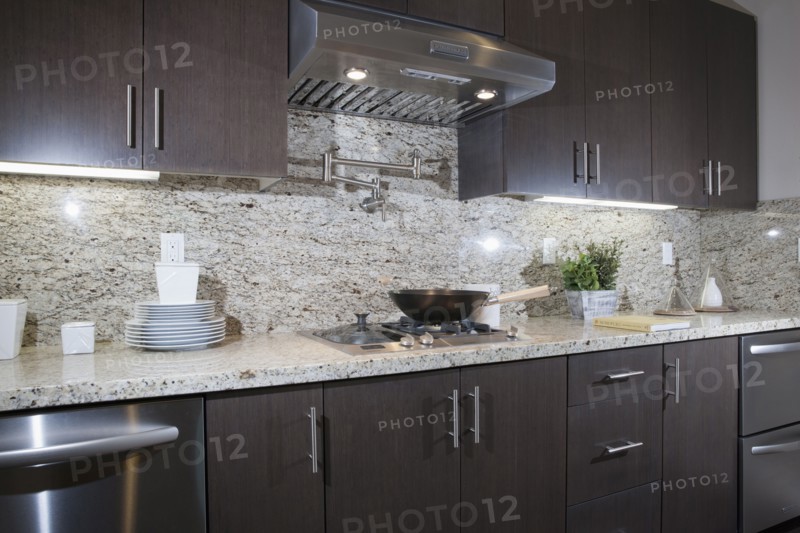 Kitchen having brown cabinets with granite counter top and wall at home