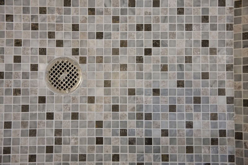 Close-up of drain in mosaic tile floor in the bathroom at home
