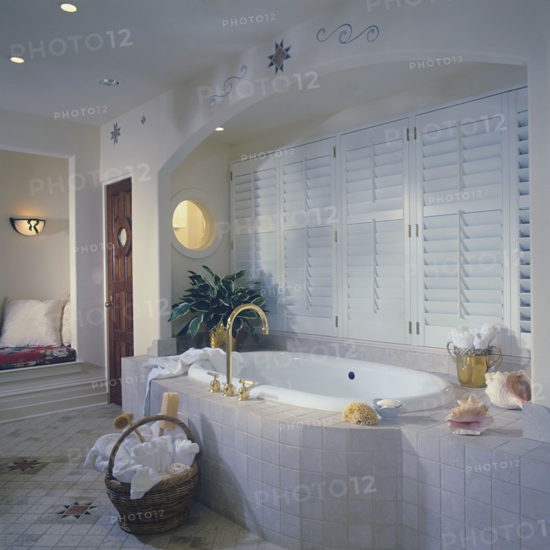Tub with tile surround set in arched alcove with shuttered windows