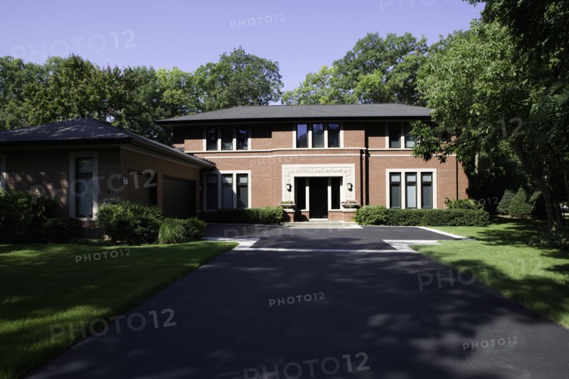 Brick contemporary  Prairie style home with blacktop driveway leading  up to home