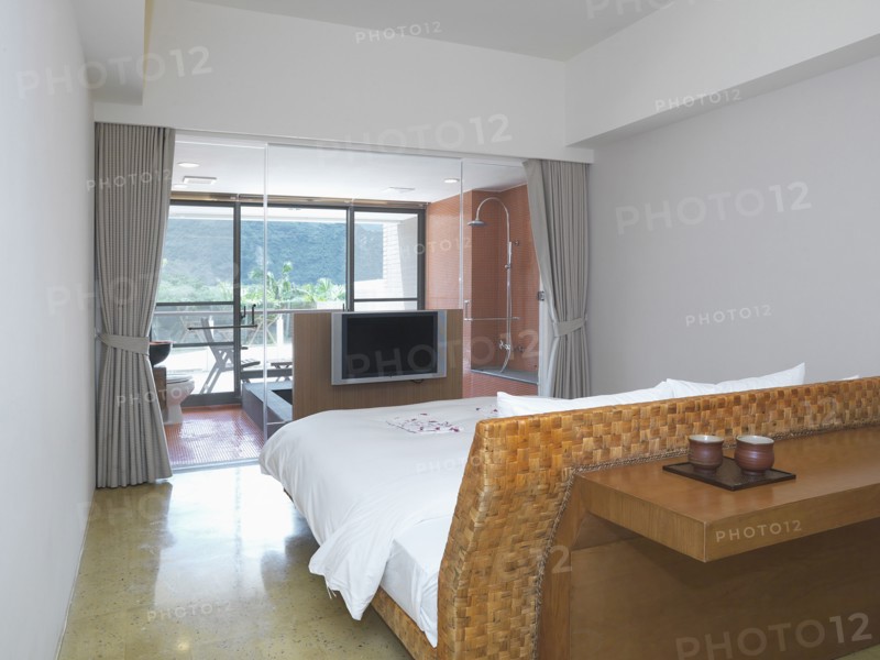 Small modern bedroom with glass wall separating from bathroom
