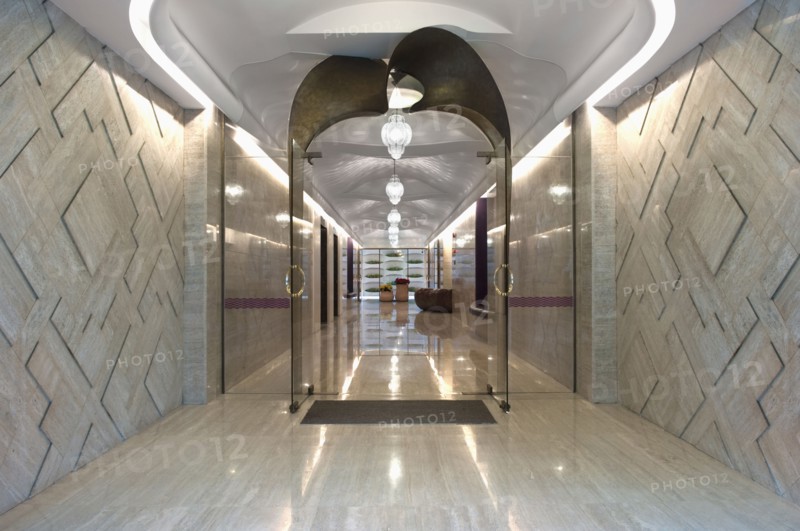 Long marble hallway with double glass doors at end