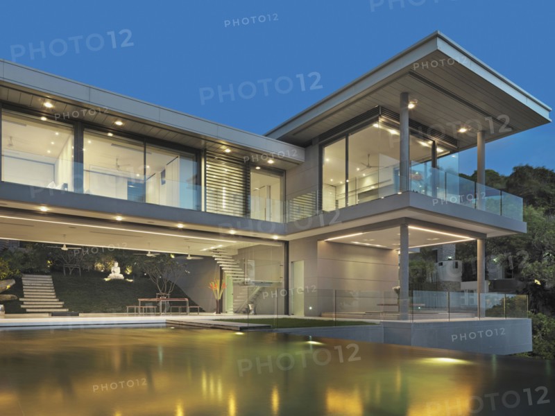 Multiple story modern home with swimming pool at dusk