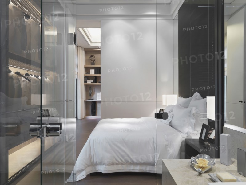 Glass door and wall separating modern bedroom from bathroom