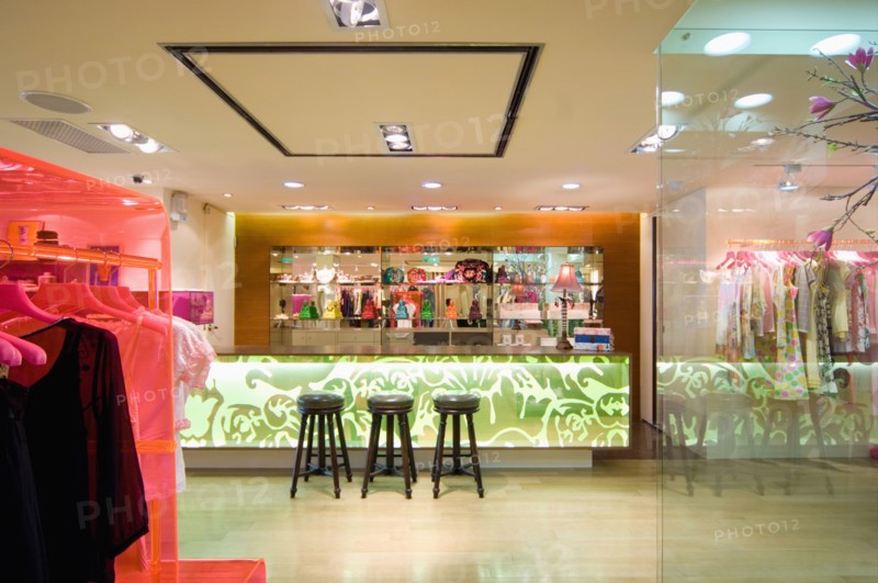 Barstools by lit counter in modern clothing store